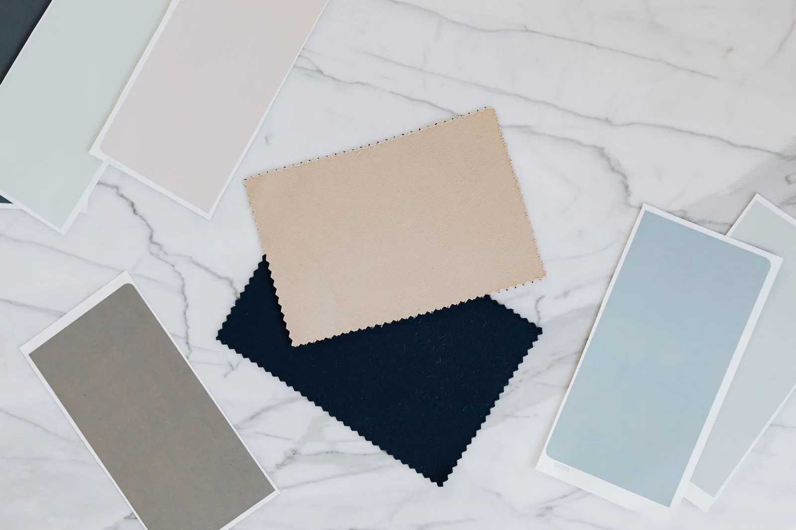 Top view of fabric and color swatches on a marble surface, ideal for interior design projects.